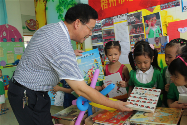 梧州市总工会党组书记、常务副主席朱明胜在梧州市总工会到梧州高新区双语实验学校开展关爱农民工留守活动中为孩子们送上学习用具