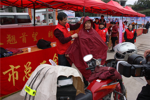 梧州市总工会的党员义工们在市东出口春运服务站助力“摩托大军”平安返乡，帮助他们检查车辆和行李，穿上雨衣。--黄贺峰摄.j